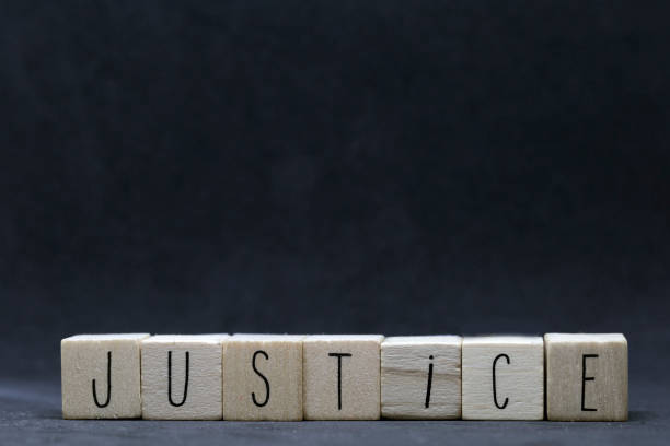 Wooden cubes with the word Justice on black background, protest concept Wooden cubes with the word Justice on black background, protest concept with hearts symbol dark social justice concept photos stock pictures, royalty-free photos & images