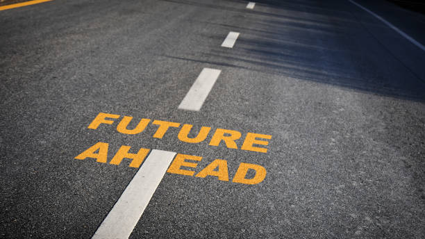 istock Future ahead word with white dividing lines on black asphalt road surface with sunlight 1251468668