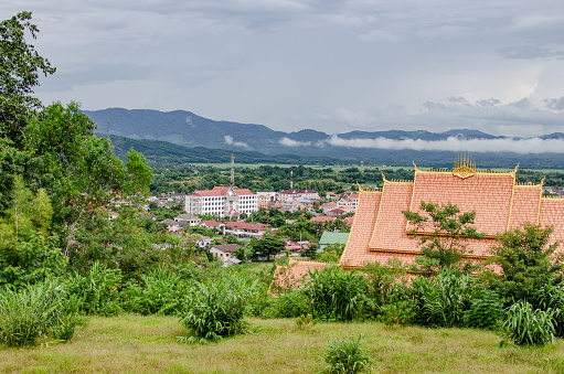 Luang Namtha, Lao - 09/04/2016: Mountain view at travel destination Luang Namtha on town, golden Buddhist temple roof top, fog green grass and jungle