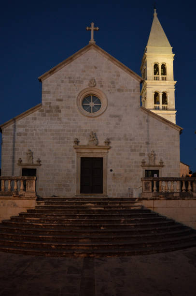 Church of St. Peter in Supetar, night photography Church of St. Peter was bulit in the 16th century by its residents. At first, the church had only space around the altar, which was covered. In the 17th century the church was expanded and, in 1612, the parish of Supetar was established. The building of the bell tower began after the construction of the church was completed, around 1627. old catholic church on island brac croatia stock pictures, royalty-free photos & images