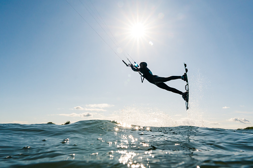 A wide-angle shot captures the serenity and excitement of kite surfing, as a skilled surfer rides the waves, framed by the vastness of the open sea.