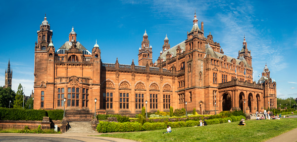 Glasgow, Scotland - People enjoying sunny weather outside the front of the Kelvingrove Art Gallery and Museum in the city's West End, with the spire of Glasgow University visible to the left of the image.