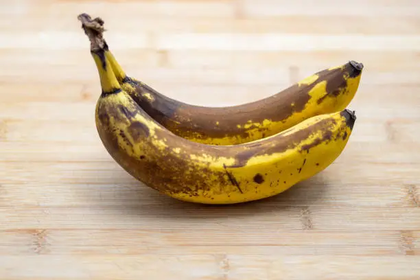 Photo of Two over ripe bananas on a wooden table