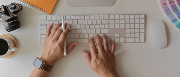 istock Male entrepreneur working with mock-up laptop on white office desk with computer, camera and coffee cup 1251480464