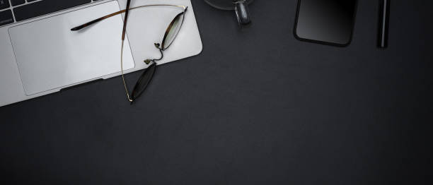 istock Dark modern workspace with open blank notebook, glasses, smartphone, cup and copy space 1251480513