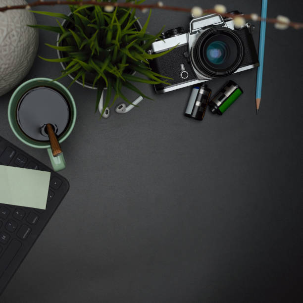 istock Dark modern workspace with coffee mug, wireless keyboard, supplies, decoration and copy space 1251480541
