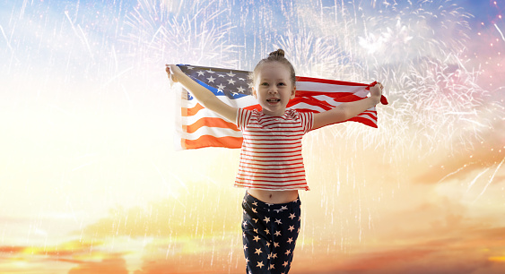 Patriotic holiday. Happy kid, cute little child girl with American flag. USA celebrate 4th of July.