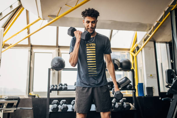 istock Man volleyball player training with dumbbells in the gym 1251483089