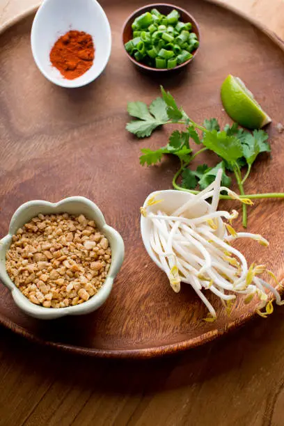 Pad Thai ingredients, sauces and garnishes. Classic Japanese Vietnamese or Thai cuisine ingredients , noodles, pork, chicken, tofu, scallions, mushrooms, cilantro, peanuts, bean sprouts eggs & pepper sauce.