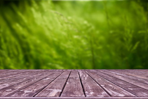 istock Mockup. Empty wooden deck table with foliage bokeh background. 1251484869
