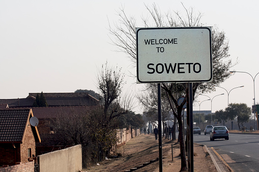 A roadside welcome banner inviting you to visit the Soweto area of Johannesburg. Road sign, road sign \