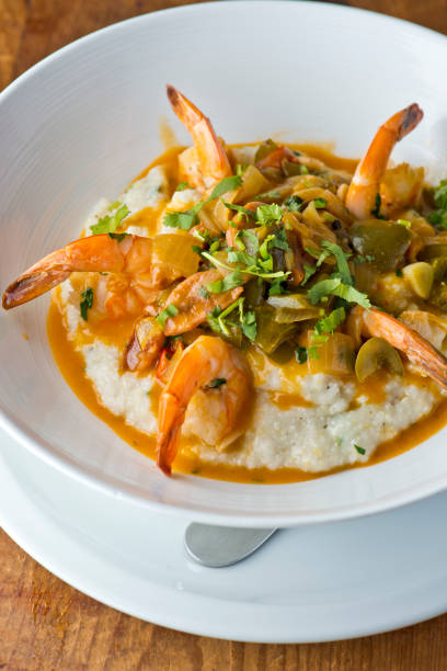 crevettes et grains. crevettes et grains, petit déjeuner ou brunch préféré, sauté dans du beurre biologique, de l’ail et servi w / gâteau de crabe en morceaux, chou-fleur et brocoli. restaurant américain classique ou français bistro entrée préf - grits prepared shrimp restaurant food photos et images de collection