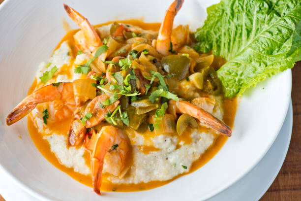 crevettes et grains. crevettes et grains, petit déjeuner ou brunch préféré, sauté dans du beurre biologique, de l’ail et servi w / gâteau de crabe en morceaux, chou-fleur et brocoli. restaurant américain classique ou français bistro entrée préf - grits prepared shrimp restaurant food photos et images de collection