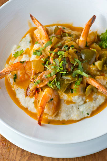 shrimp and grits. shrimp and grits, breakfast or brunch favorite, sautéed in organic butter, garlic & served w/  jumbo lump crab cake, cauliflower and broccoli. classic american restaurant or french bistro entree favorite. - grits prepared shrimp restaurant food imagens e fotografias de stock