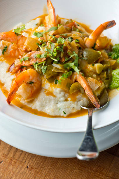 shrimp and grits. shrimp and grits, breakfast or brunch favorite, sautéed in organic butter, garlic & served w/  jumbo lump crab cake, cauliflower and broccoli. classic american restaurant or french bistro entree favorite. - grits prepared shrimp restaurant food imagens e fotografias de stock