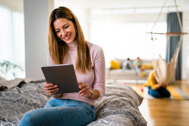 istock Beautiful young woman using digital tablet and smiling while sitting at home 1251488665