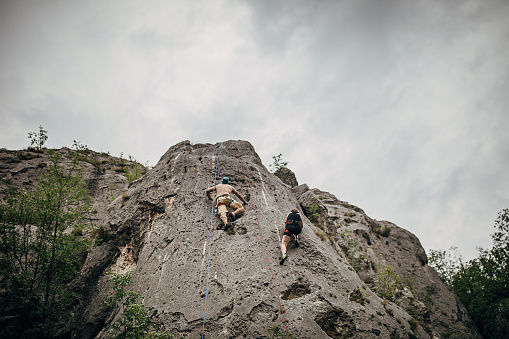 Man and woman, free climbers, climbing on the rock mountain in nature.