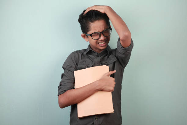 istock Young boy holding books in hand with a stressed face expression 1251491397