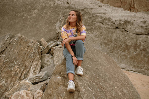 istock Young woman sitting on a rock 1251492601