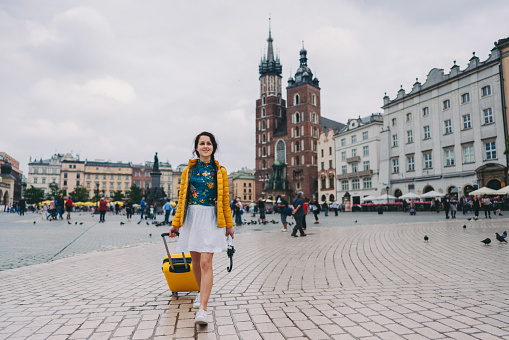 Smiling woman with suitcase just arriving in Krakow and enjoying the amazing city
