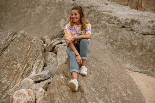 istock Young woman sitting on a rock 1251494019