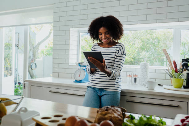 istock Mixed race woman browsing digital tablet in the kitchen at home 1251494349