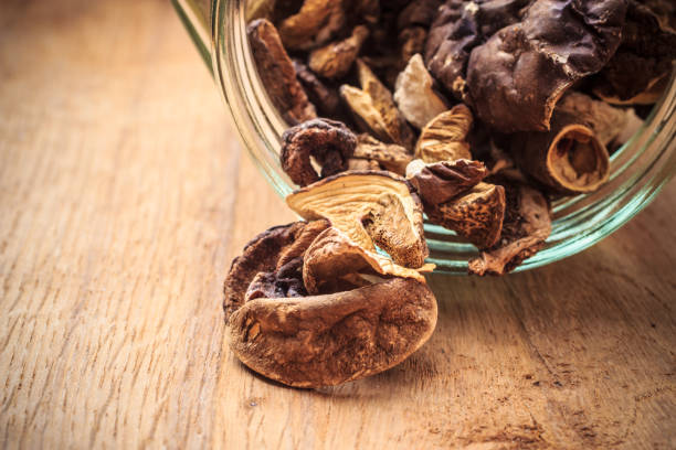 istock Dry mushrooms in jar on wooden table. 1251495667