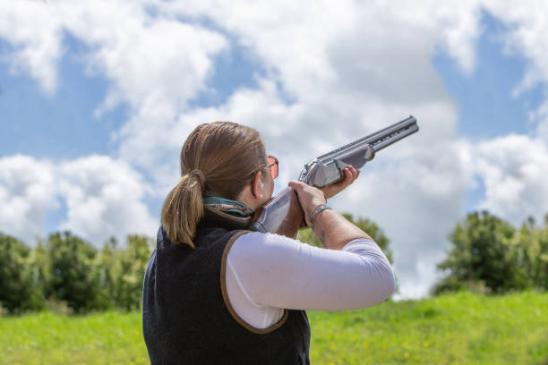 Portrait of a young woman sport trap clay shooter in a classic shooting pose. stock photo