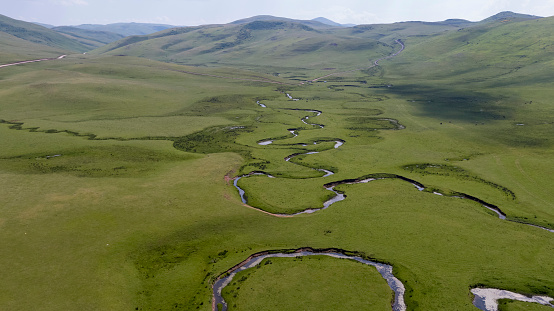 Meandering stream with mountains and clouds at The Persembe Plateau at Ordu, Turkey.