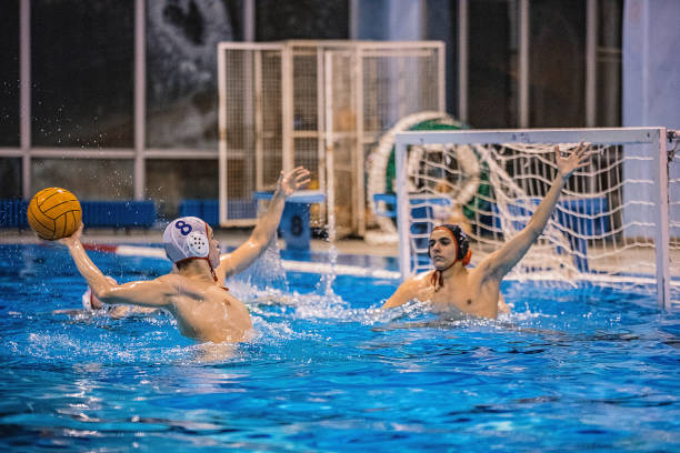 istock Man scoring a goal in water polo game indoors 1251500736