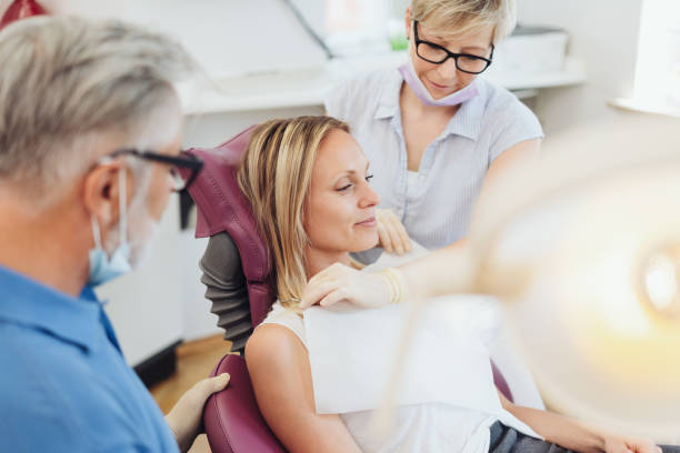 istock Dental assistant placing a bib on a female patient 1251504370