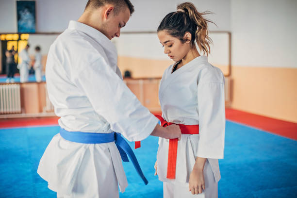 istock Young male karate trainer tying belt for his student 1251509968