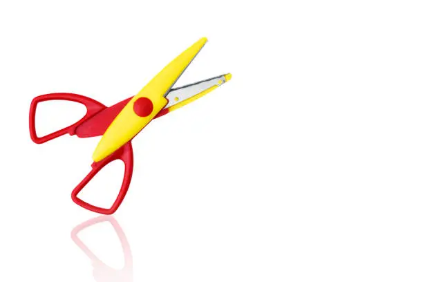 Red-yellow colored plastic open scissors isolated on a white background, with reflection.