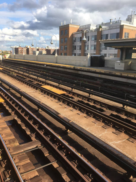 istock Overground train tracks at an empty subway platform in Queens, NY. Empty subway platform.  Outdoor subway station stop in New York City.  Vacant city. Apartment buildings in the background. 1251512638