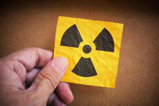 istock Man holding radiation warning sign in his hand 1251513919
