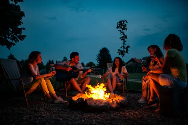 Playing guitar and singing around the bonfire at night.