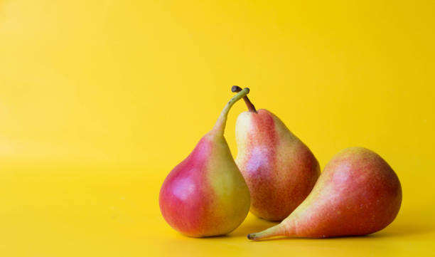 istock Three red yellow fresh pears isolated on  yellow background. 1251515344
