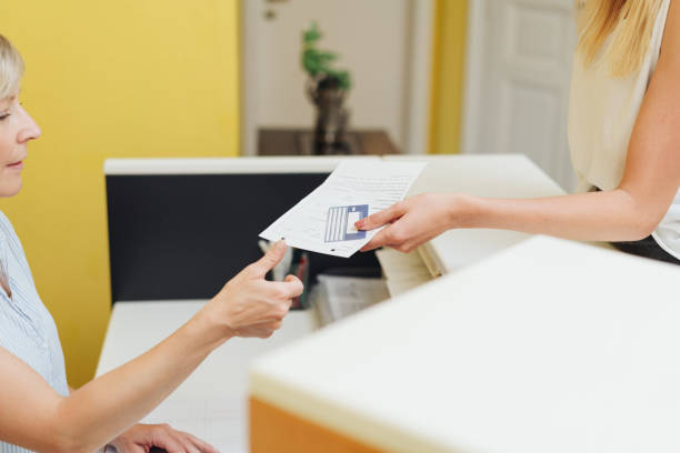 istock Patient handing over a completed registration form 1251515784