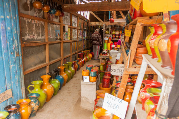 October 20, 2019 - Pomaire, Chile: Tourists costumers looking and buying souvenirs and greda earthenware pots in a pile group of chilean classic rustic handmade baked terra-cotta greda clay flower pots, plates, friers for sale in a the pottery workshop and store.