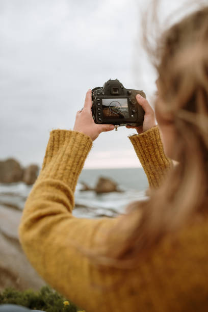 istock Young woman using a DSLR camera by the sea 1251517447