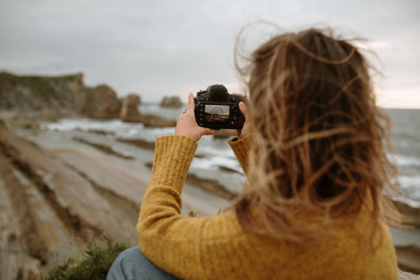 Young woman using a DSLR camera by the sea at the sunset