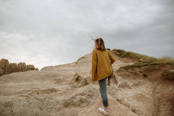 istock Young woman standing on rocks 1251520718