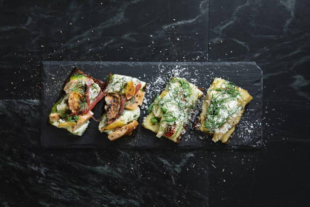 Traditional Danish Smorrebrod with Salted saffron mushrooms, potato and homemade mayonnaise. Artichoke, dried tomatoes and goat cheese. Flat lay top-down composition on black background. Horizontal image with copy space.