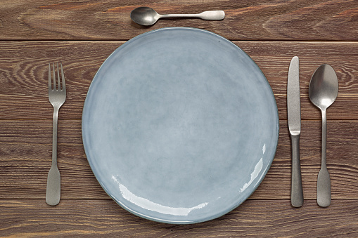 Ceramic plate and cutlery on a wooden worktop