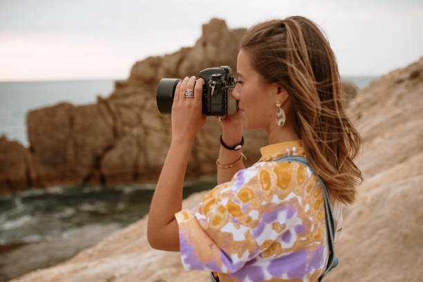 istock Young woman using a DSLR camera by the sea 1251525734