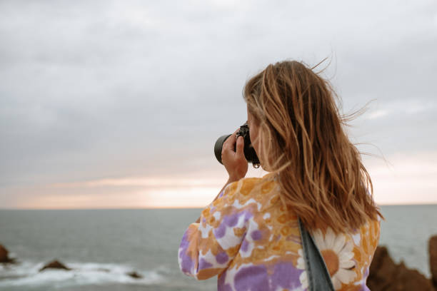 istock Young woman using a DSLR camera by the sea 1251526414