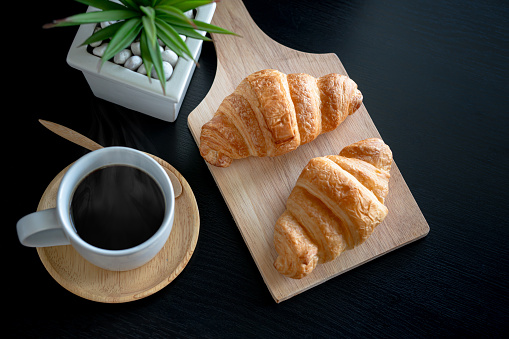 French breakfast: croissant bread and black coffee on table