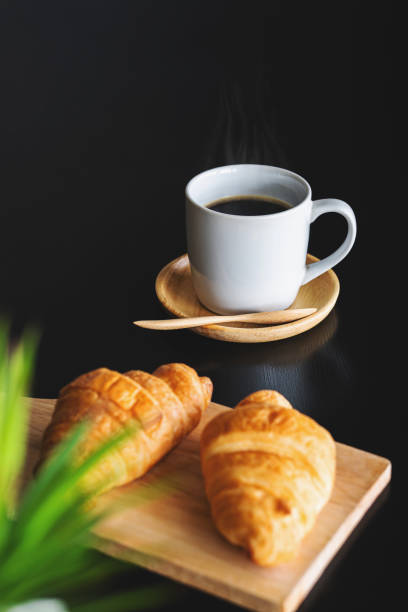 istock Two fresh croissants and cup of coffee on dark stone table 1251526716