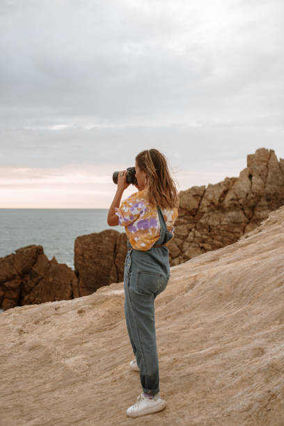istock Young woman using a DSLR camera by the sea 1251527851