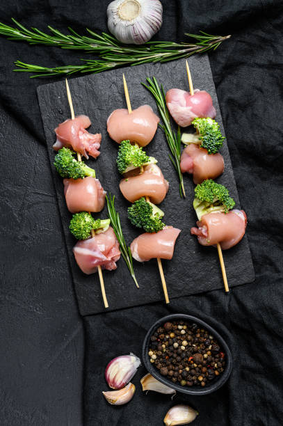 istock Raw chicken shish kebab with broccoli,  Barbecue. Black background. Top view 1251528369